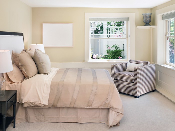 Chambre à coucher peinte dans des couleurs vives, contenant un lit et un fauteuil d’appoint.