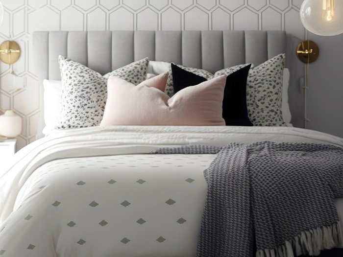 Sur le lit, une couette avec des formes géométriques et des coussins d’appoint.