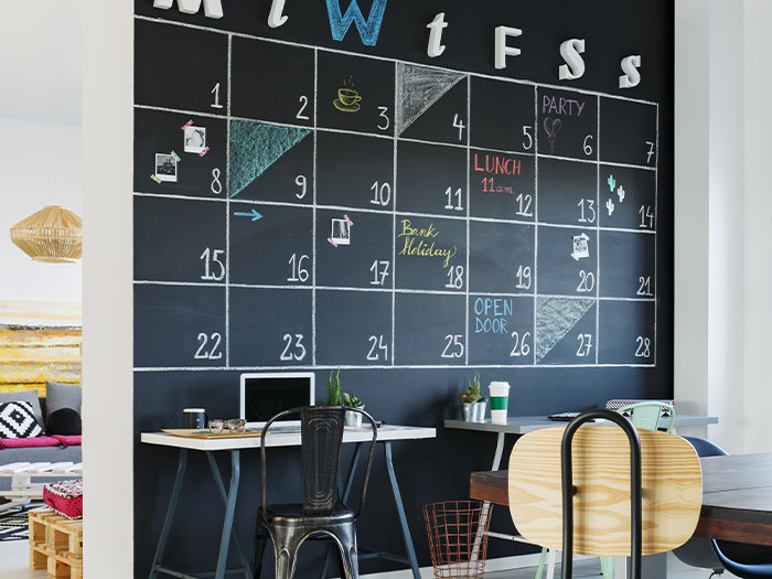 Bureau avec un mur de tableau noir utilisé comme calendrier.
